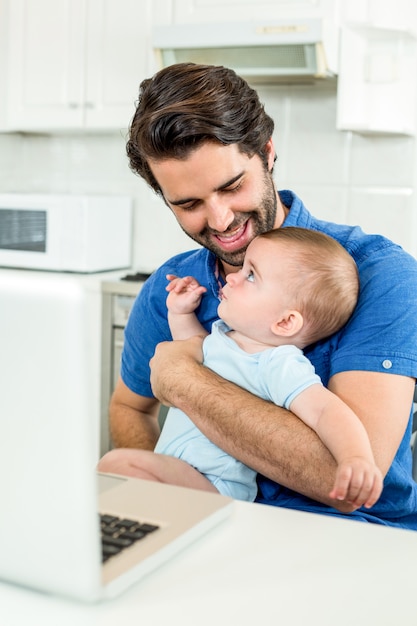 Mann, der bei Tisch mit Sohn durch Laptop sitzt