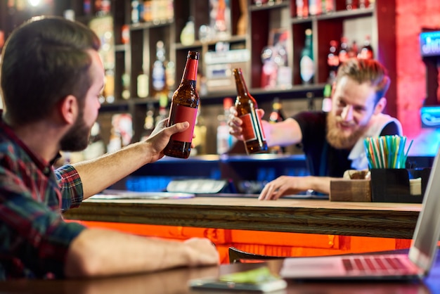 Foto mann, der bierflaschen mit barkeeper klirrt