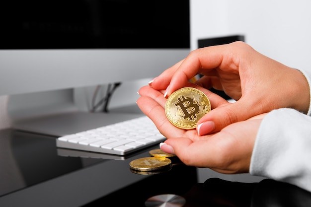 Mann, der Bitcoin-Münze in der Hand auf Holzhintergrund hält