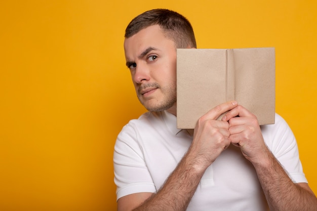 Mann, der Buch nahe Gesicht auf Gelb hält