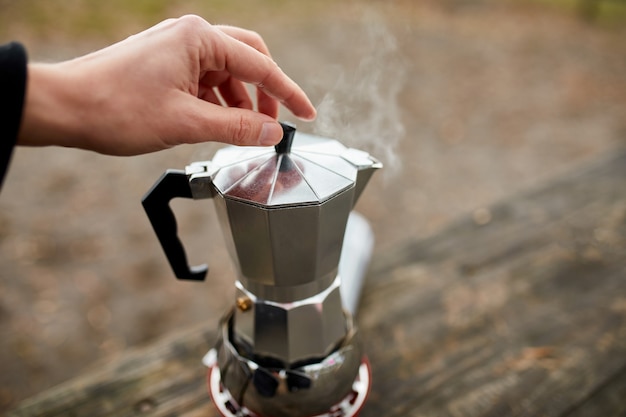 Mann, der Campingkaffee im Freien mit Metallgeysir-Kaffeemaschine auf einem Gasbrenner macht, Schritt für Schritt.
