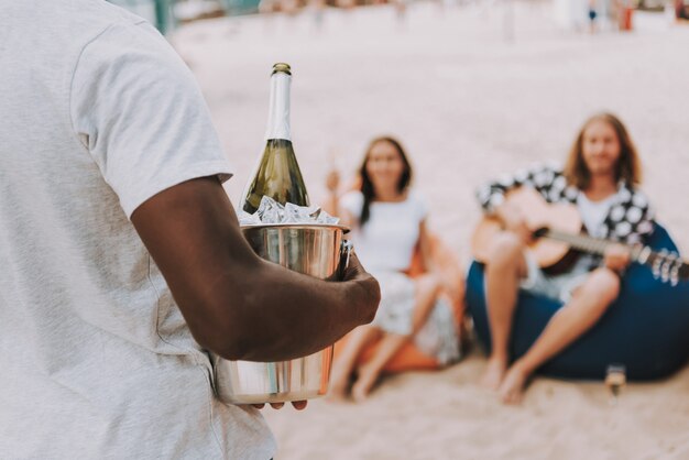 Mann, der Champagne im Eiseimer-Strandfest hält