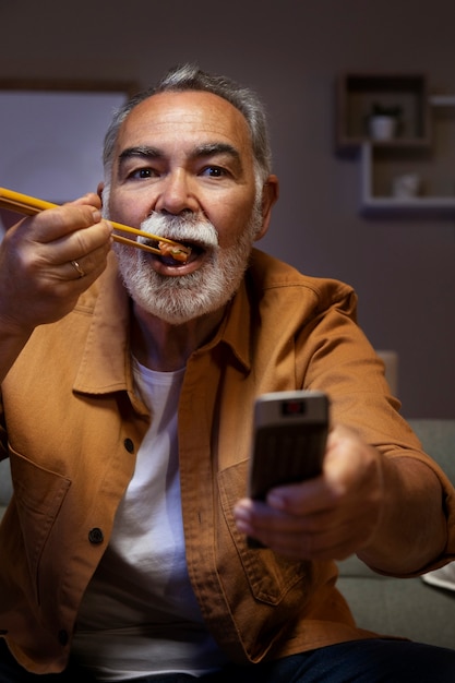 Foto mann, der das essen genießt, während er allein zu hause ist und fernsieht