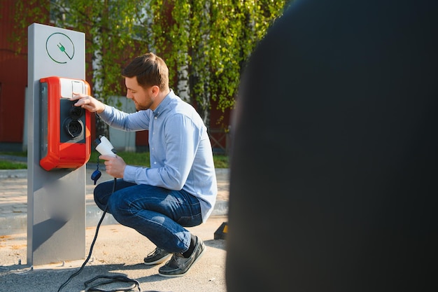 Mann, der das Ladekabel für Elektroautos hält