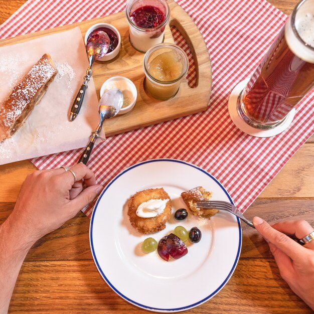 Mann, der den süßen Nachtischsnack der Marmelade mit dem dunklen schwarzen Bier isst