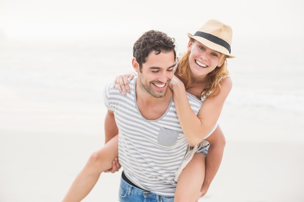 Mann, der der Frau auf dem Strand ein Doppelpol gibt