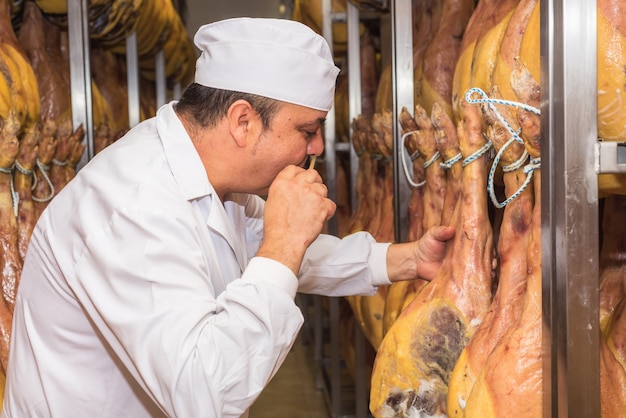 Mann, der die Heilung von spanischem jamon steuert. Lebensmittel-Industrie-Konzept.