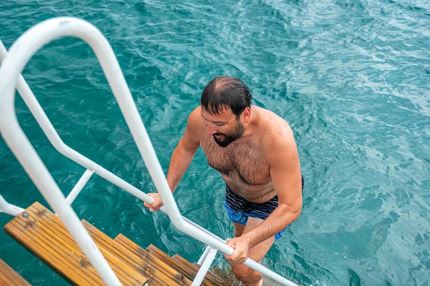 Mann, der die Treppe hinaufsteigt, nachdem er seinen Sprung im Wasser beendet hat