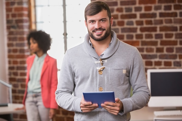 Mann, der digitale Tablette mit Kollegen hinten im Büro verwendet