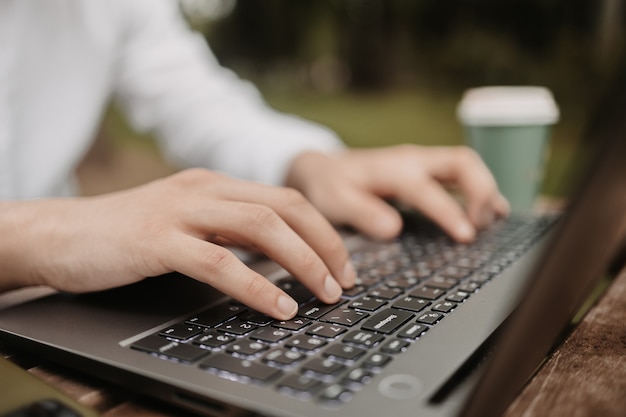 Mann, der draußen auf der Tastatur tippt. Freiberufler, der aus der Ferne arbeitet.