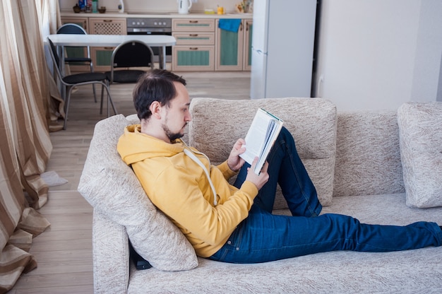 Mann, der ein Buch auf der Couch liest