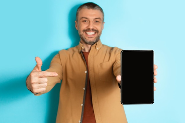 Mann, der ein digitales Tablet zeigt, das mit dem Finger auf den blauen Hintergrund des Bildschirms zeigt