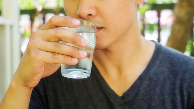 Mann, der ein Glas Wasser und ein Getränk anhält.