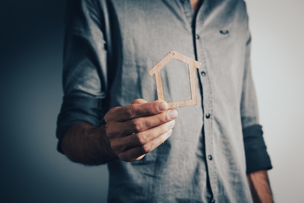 Mann, der ein kleines Haus in seiner Hand hält