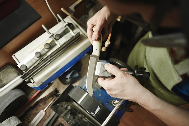 Mann, der ein Messer in der Werkstatt schärft