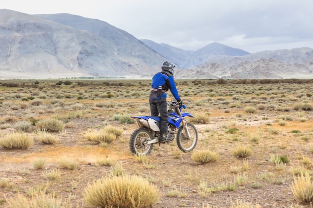 Mann, der ein Motorradkreuzrad in den Steppen der Mongolei, auf den Hügeln der Mongolei reitet
