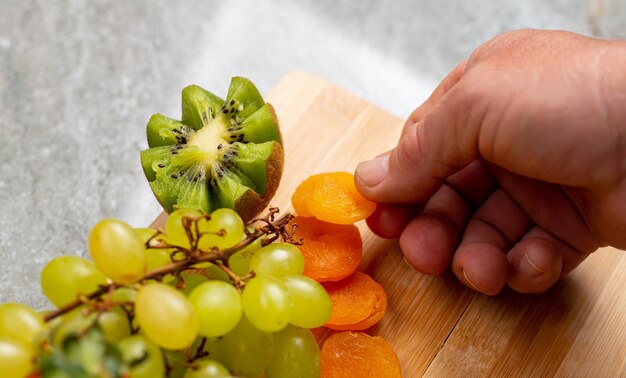 Mann, der ein Obstbrett mit grüner Traube, Aprikose, Erdbeere anordnet.