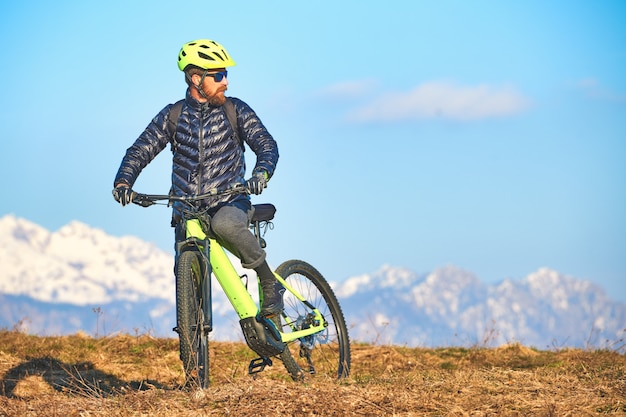 Mann, der eine Bergwiese mit Mountainbike klettert