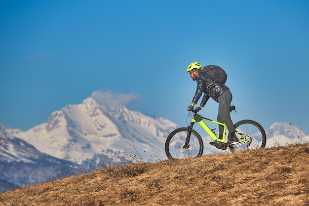 Mann, der eine Bergwiese mit Mountainbike klettert