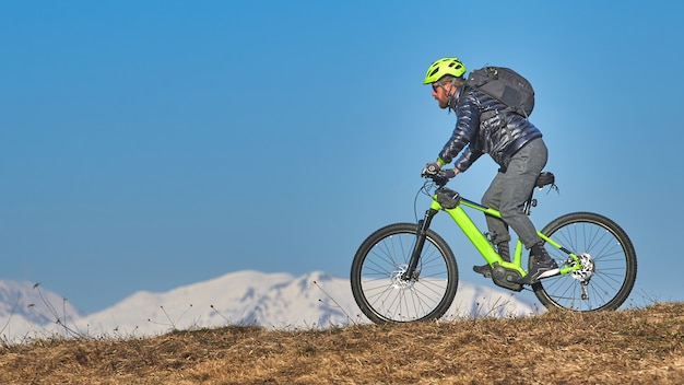 Mann, der eine Bergwiese mit Mountainbike klettert