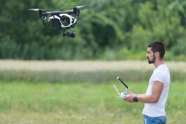 Mann, der eine Drohne fliegt oder per Fernbedienung in der Natur schwebt