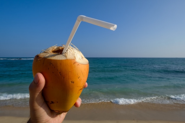 Mann, der eine Kokosnuss am Strand hält