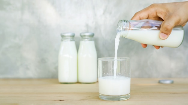 Mann, der eine Milch auf einen Holztisch gießt.