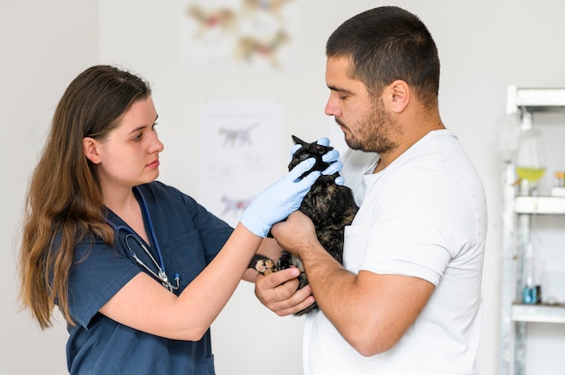 Foto mann, der eine schwarze katze hält, während der tierarzt die diagnose und behandlung des haustierzustands überprüft