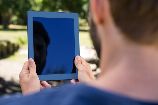 Mann, der eine Tablette im Park verwendet