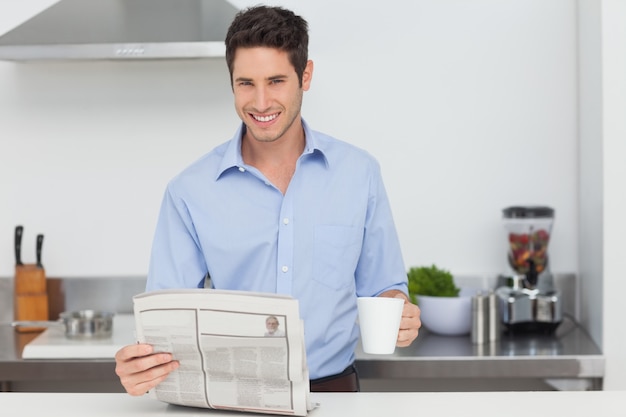 Mann, der eine Zeitung liest und eine Tasse Kaffee hält