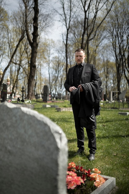 Foto mann, der einem grabstein auf dem friedhof respekt zollt