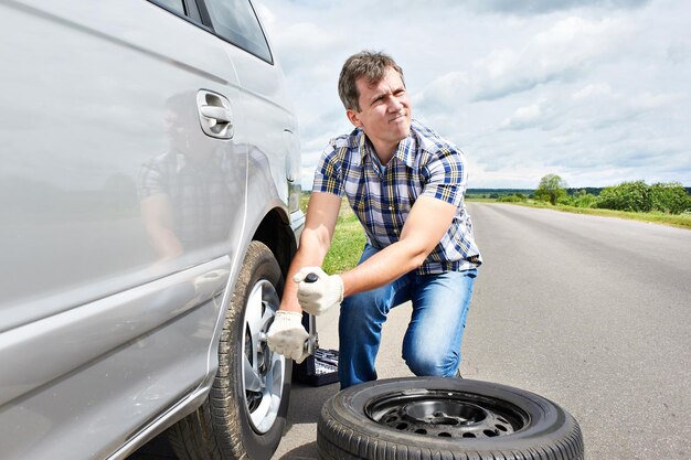 Mann, der einen Ersatzreifen des Autos wechselt