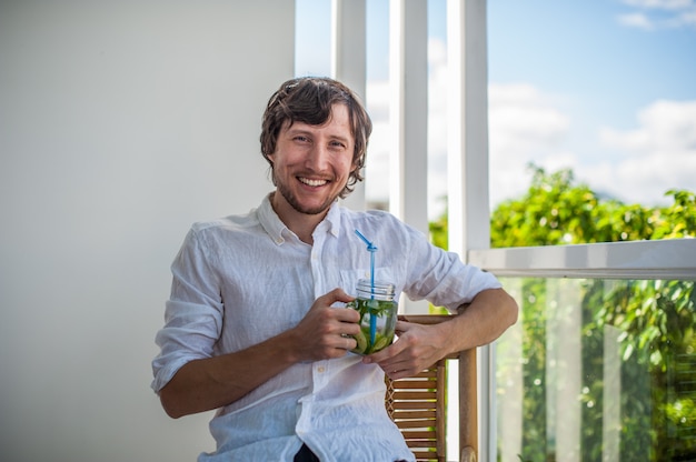 Mann, der einen Mojito auf der Terrasse trinkt.