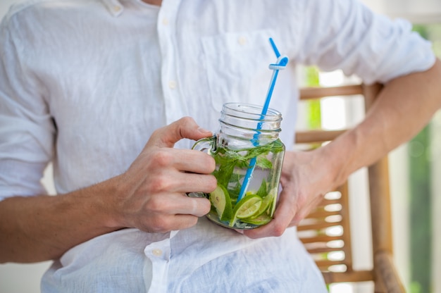 Mann, der einen Mojito auf der Terrasse trinkt.