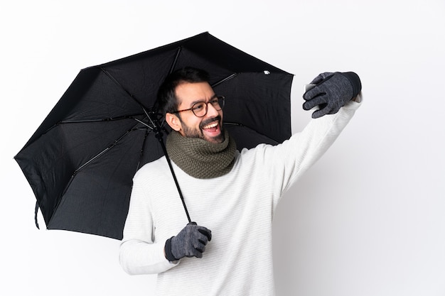 Mann, der einen Regenschirm über lokalisierter Wand hält