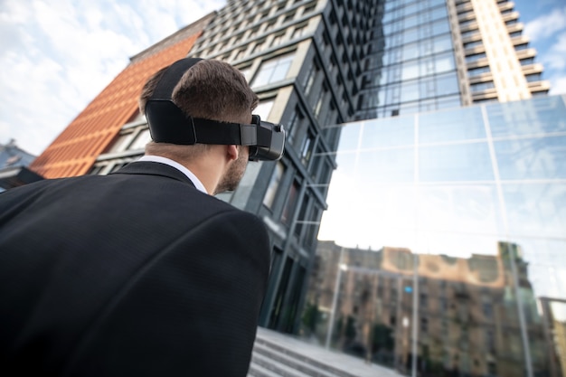 Foto mann, der einen schwarzen anzug in vr brille betrachtet, die das gebäude betrachtet