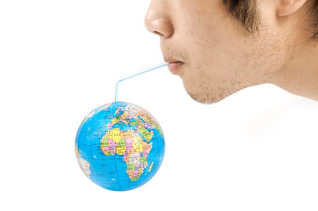 Foto mann, der einen strohhalm von einem globus mit afrika darauf trinkt