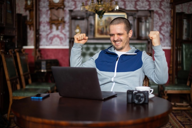 Mann, der Erfolg hat. Freiberufler mit Ergebnis zufrieden. Lächeln und in Laptop schauen.