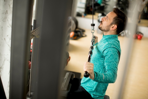 Mann, der excersise auf einer Latmaschine in der Turnhalle tut