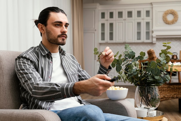 Foto mann, der fernsieht und popcorn-seitenansicht isst