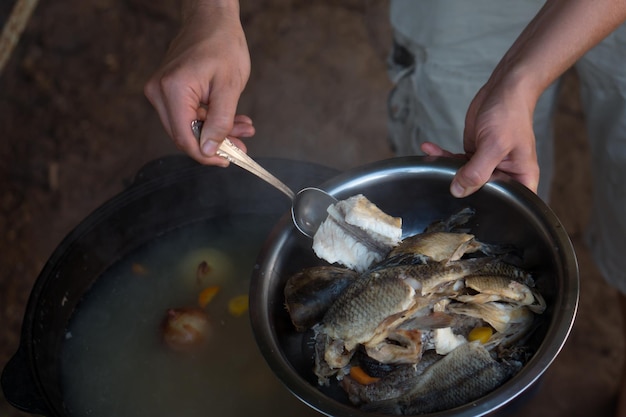 Mann, der Fischsuppe im Kessel am Lagerfeuer im Freien kocht