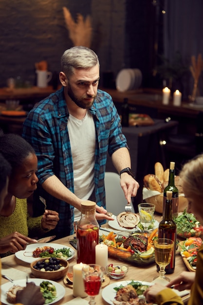 Mann, der Fleisch am Esstisch schneidet