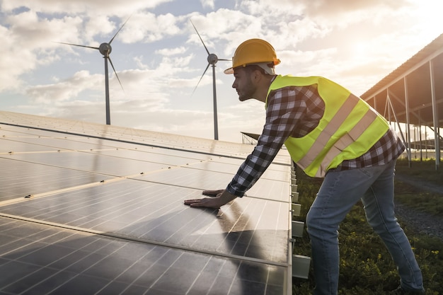 Mann, der für Sonnenkollektoren und Windkraftanlagen arbeitet - Konzept für erneuerbare Energien - Fokus auf männliche Arbeiterhände