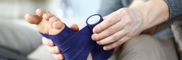 Mann, der Füße mit elastischem Verband einwickelt