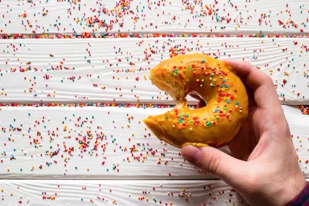 Mann, der gebissenen Donut auf einem weißen Hintergrund hält