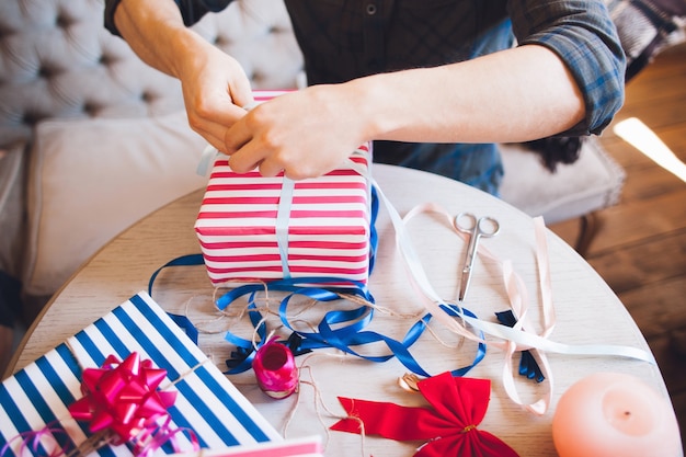 Mann, der Geschenkbox mit Band verziert.