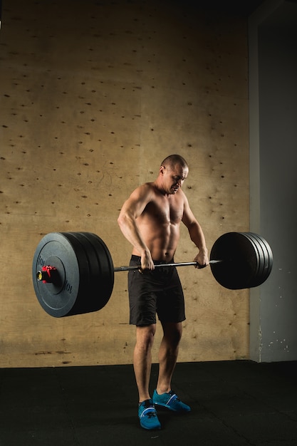 Mann, der Gewichte hebt. Muskelmann-Training im Fitnessstudio, das Übungen mit Langhantel macht