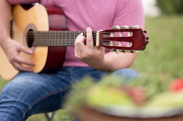 Foto mann, der gitarre draußen neben grill spielt