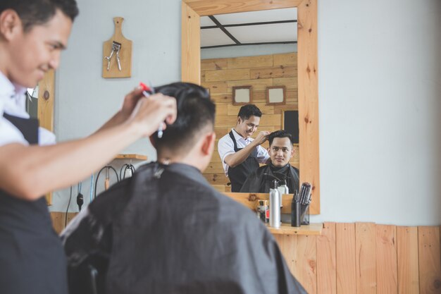 Mann, der Haarschnitt durch Friseur am Friseursalon bekommt