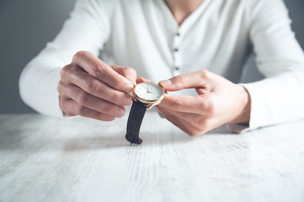 Mann, der Hand auf seiner Uhr auf Schreibtisch hält